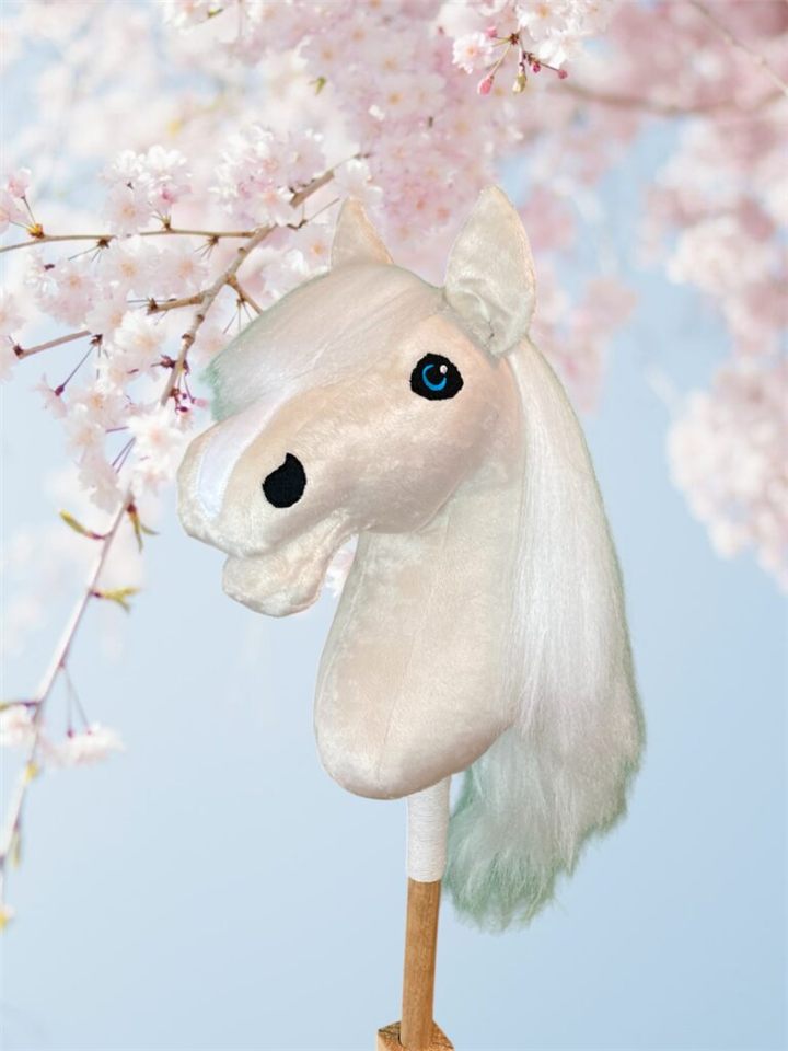 Wit hobby horse met lange manen voor roze bloesem